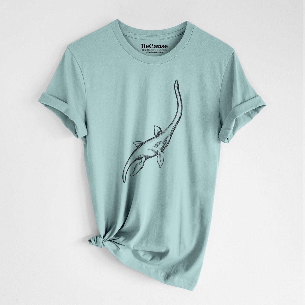Dusty blue lightweight cotton t-shirt laid flat with the sleeves rolled, printed with a black ink illustration of a long-necked plesiosaur swimming.