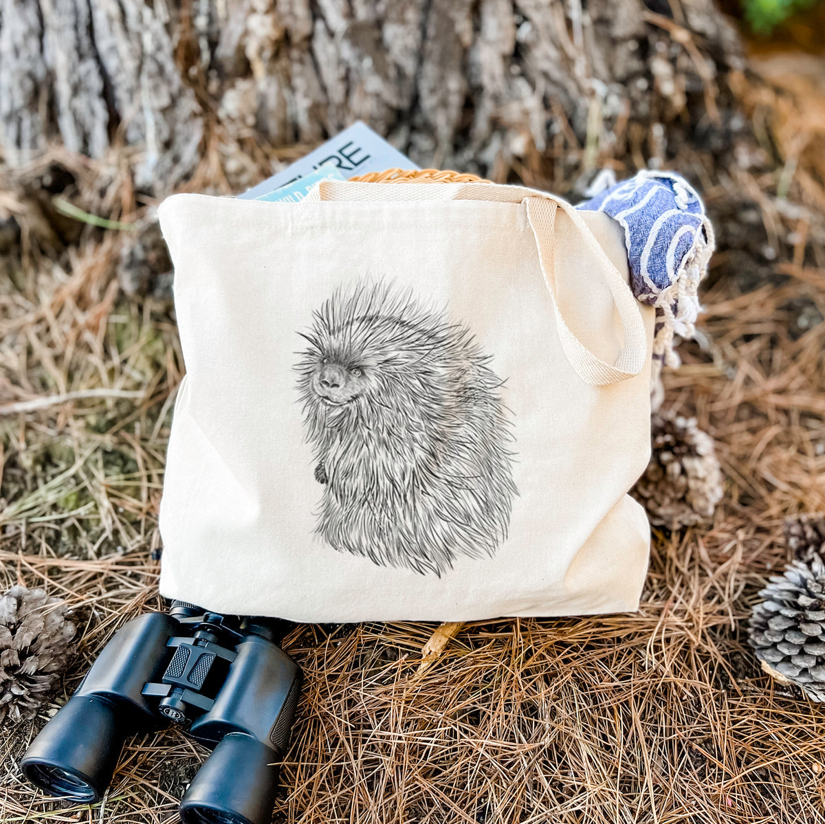 Canvas tote bag printed with a detailed black ink illustration of a porcupine with its quills raised, resting on dry grass beside a pair of binoculars.
