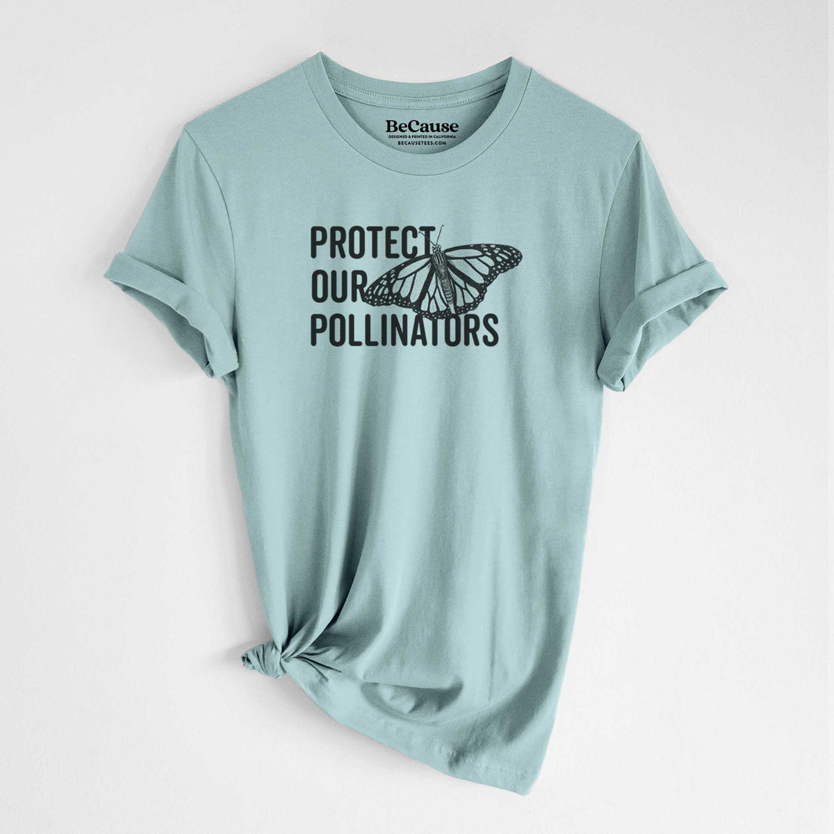 Dusty blue lightweight cotton t-shirt laid flat with the sleeves rolled, printed with bold black words reading Protect Our Pollinators beside a monarch butterfly.
