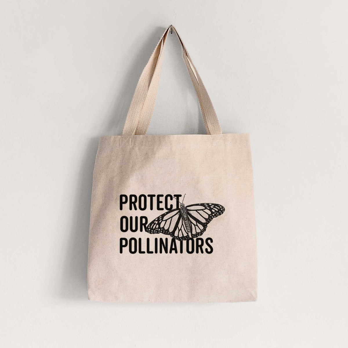 Natural canvas tote bag printed with bold black words reading Protect Our Pollinators beside a monarch butterfly.