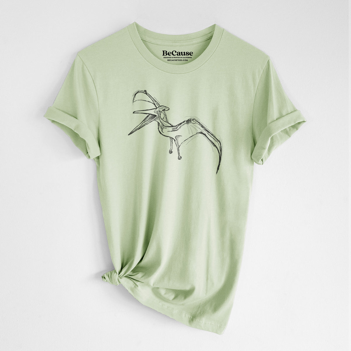 Spring green lightweight cotton t-shirt laid flat with the sleeves rolled, printed with a black ink illustration of a Pteranodon in flight.