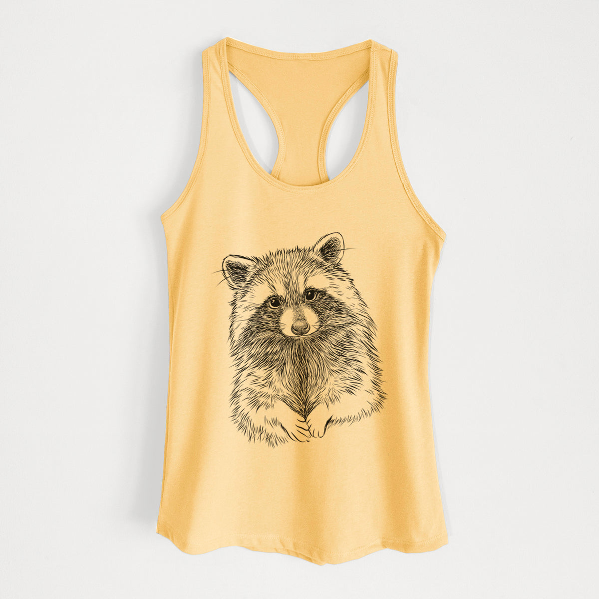 Banana cream women's racerback tank top laid flat, printed with a detailed black ink portrait of a raccoon with its front paws resting in front of it.