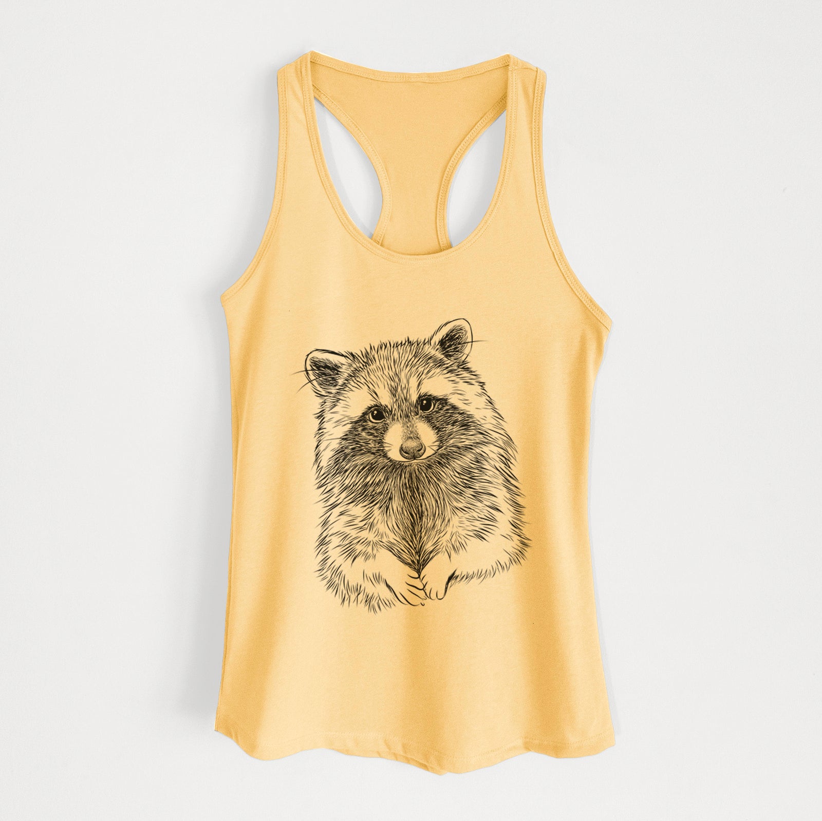 Banana cream women's racerback tank top laid flat, printed with a detailed black ink portrait of a raccoon with its front paws resting in front of it.