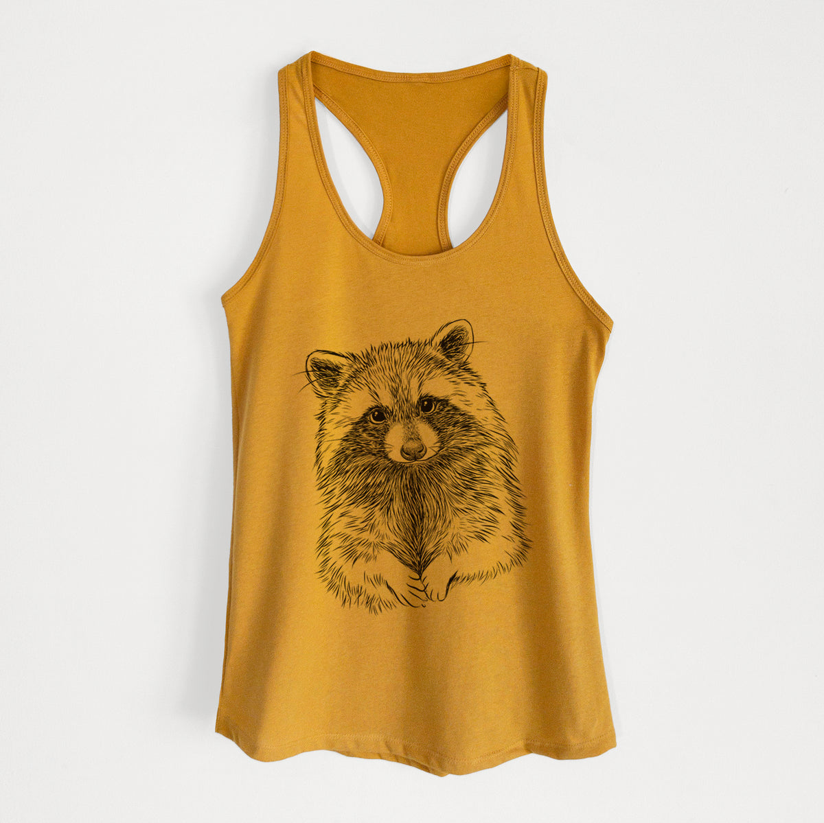 Gold women's racerback tank top laid flat, printed with a detailed black ink portrait of a raccoon with its front paws resting in front of it.