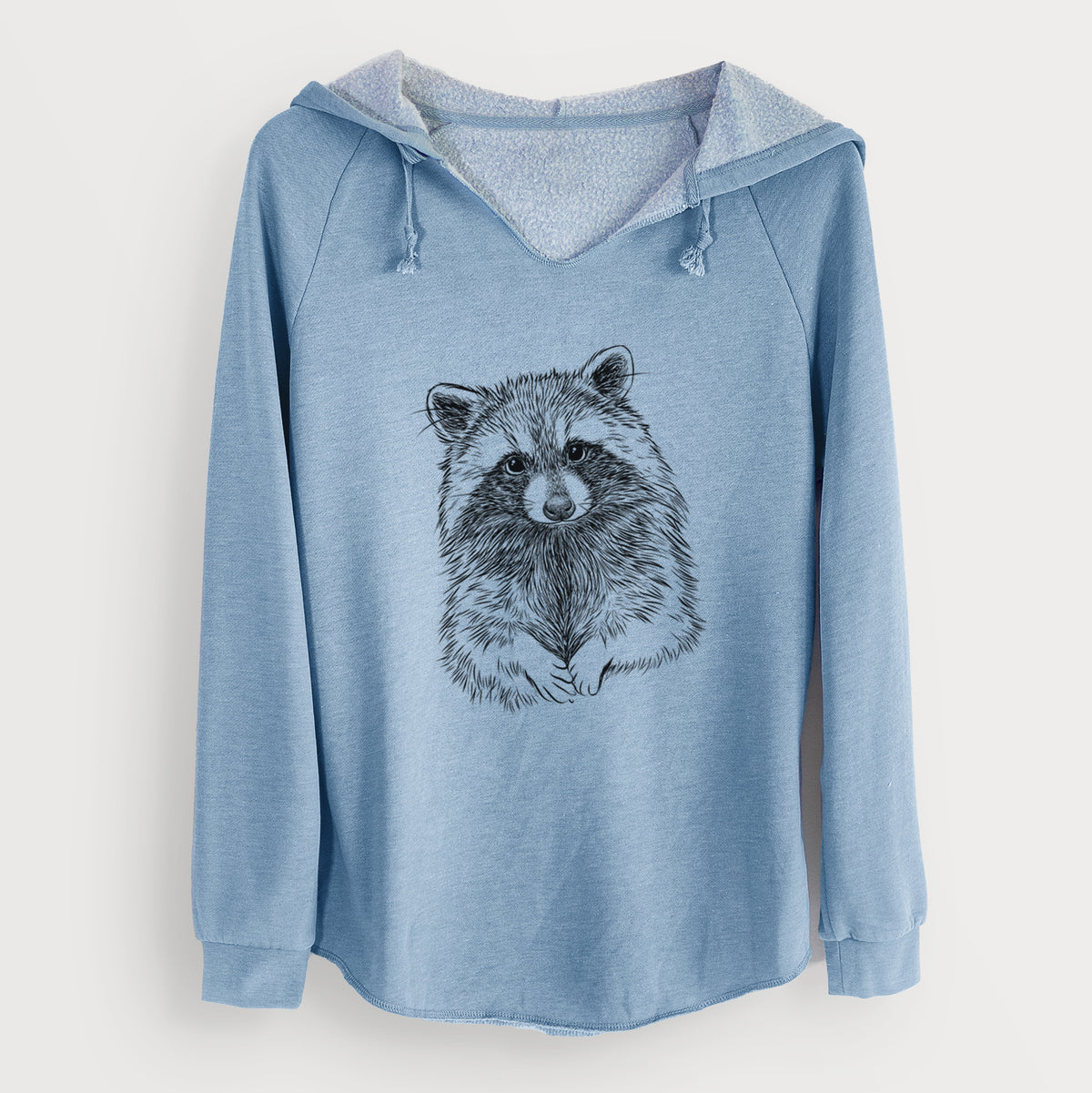 Misty blue women's Cali Wave hooded sweatshirt laid flat, printed with a detailed black ink portrait of a raccoon with its front paws resting in front of it.