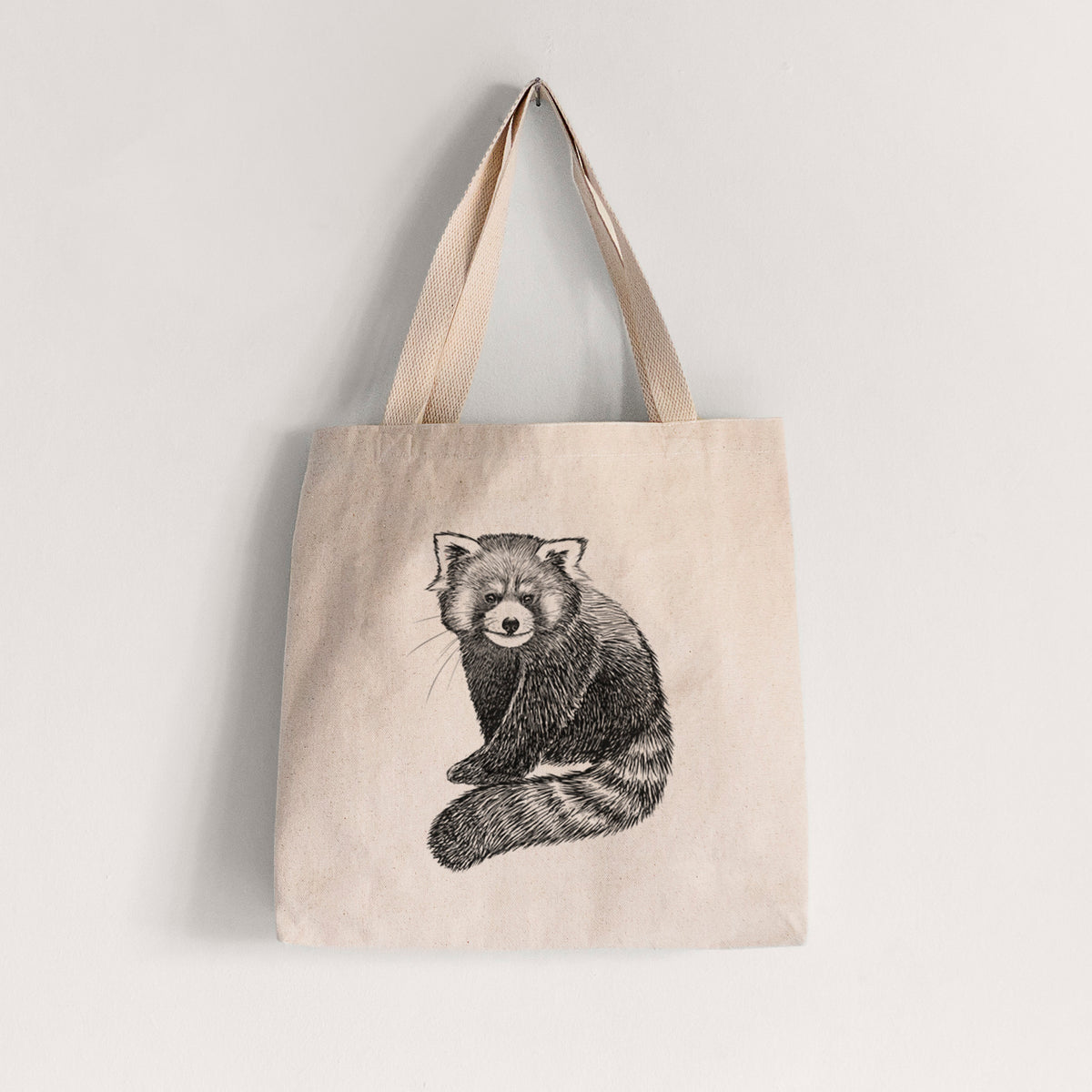 Natural canvas tote bag printed with a detailed black ink illustration of a red panda sitting with its striped tail wrapped around.
