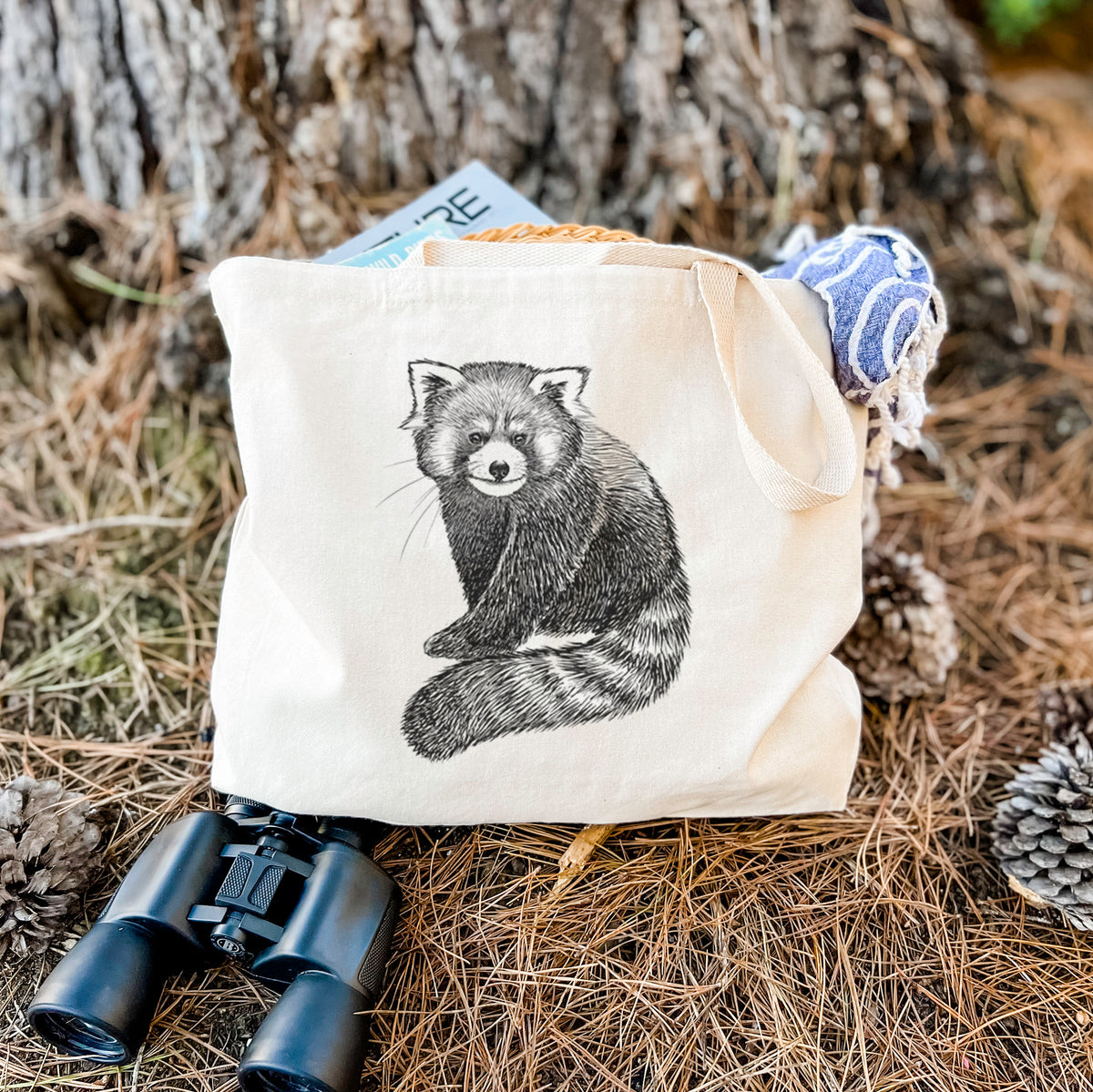 Canvas tote bag printed with a detailed black ink illustration of a red panda sitting with its striped tail wrapped around, resting on dry grass beside a pair of binoculars.