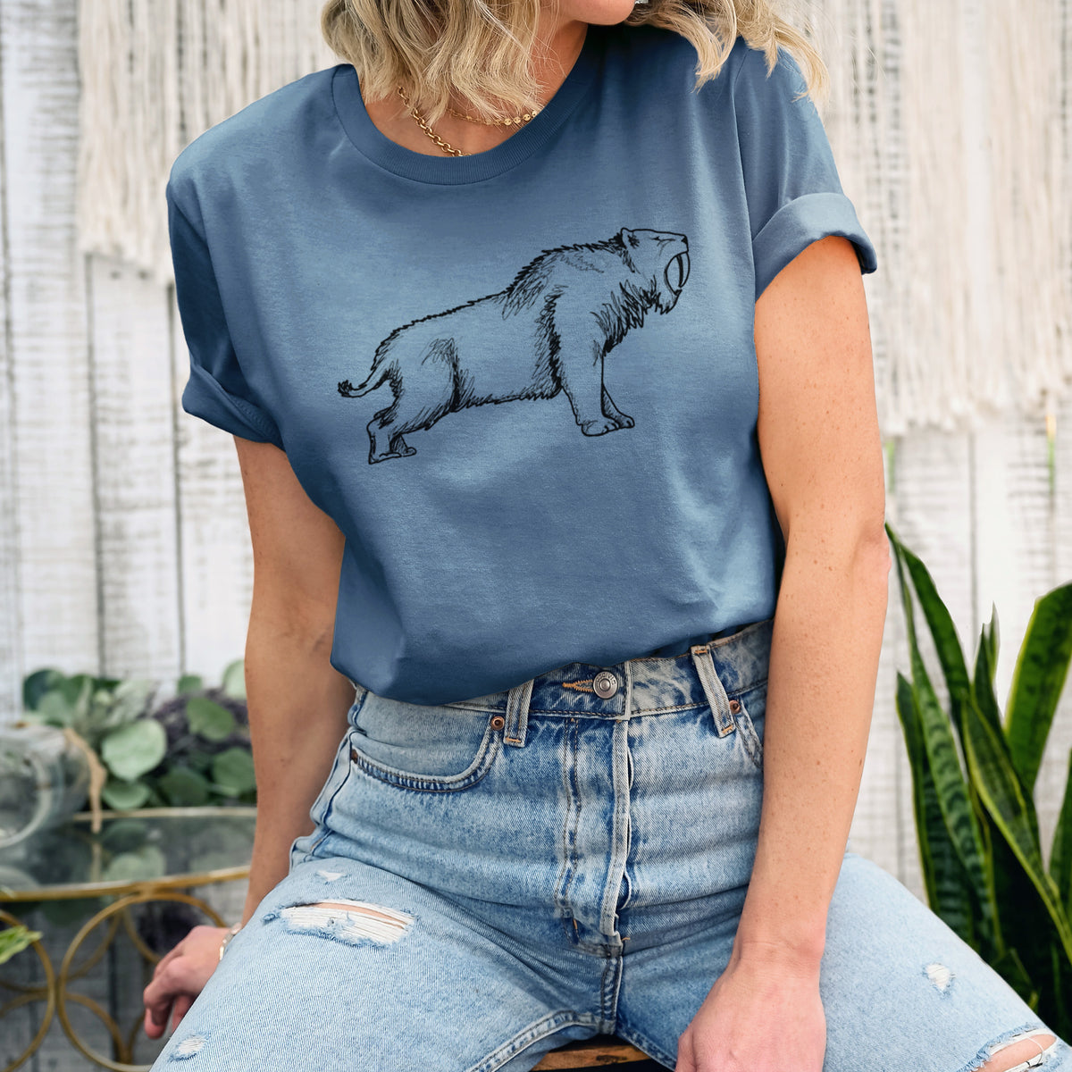 Woman wearing a steel blue lightweight cotton t-shirt printed with a black ink illustration of a saber-toothed tiger walking.