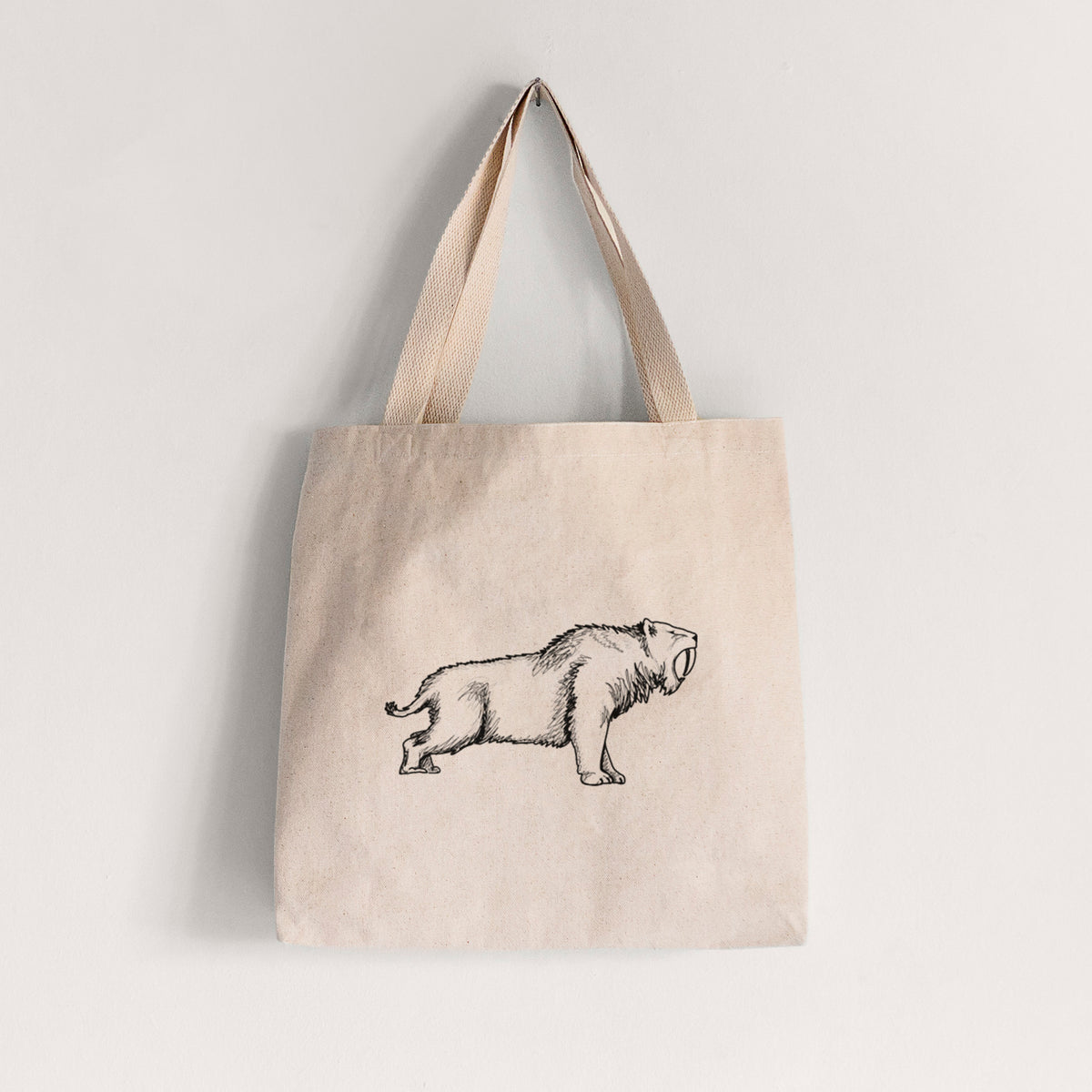 Natural canvas tote bag printed with a black ink illustration of a saber-toothed tiger walking.