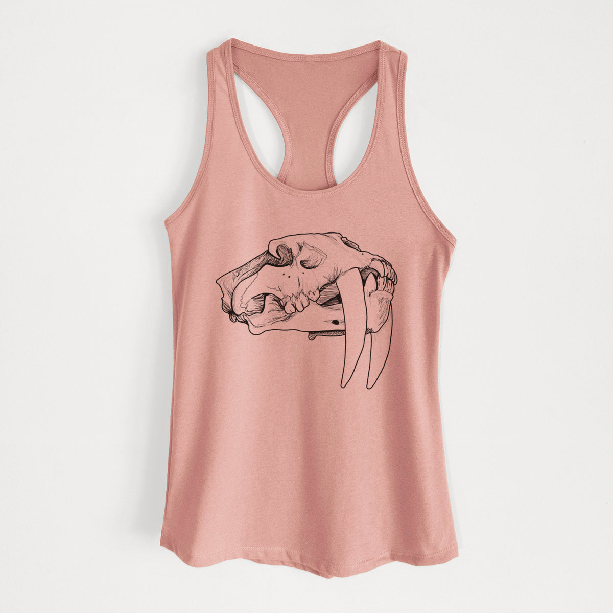 Desert pink women's racerback tank top laid flat, printed with a detailed black ink illustration of a saber-toothed tiger skull.