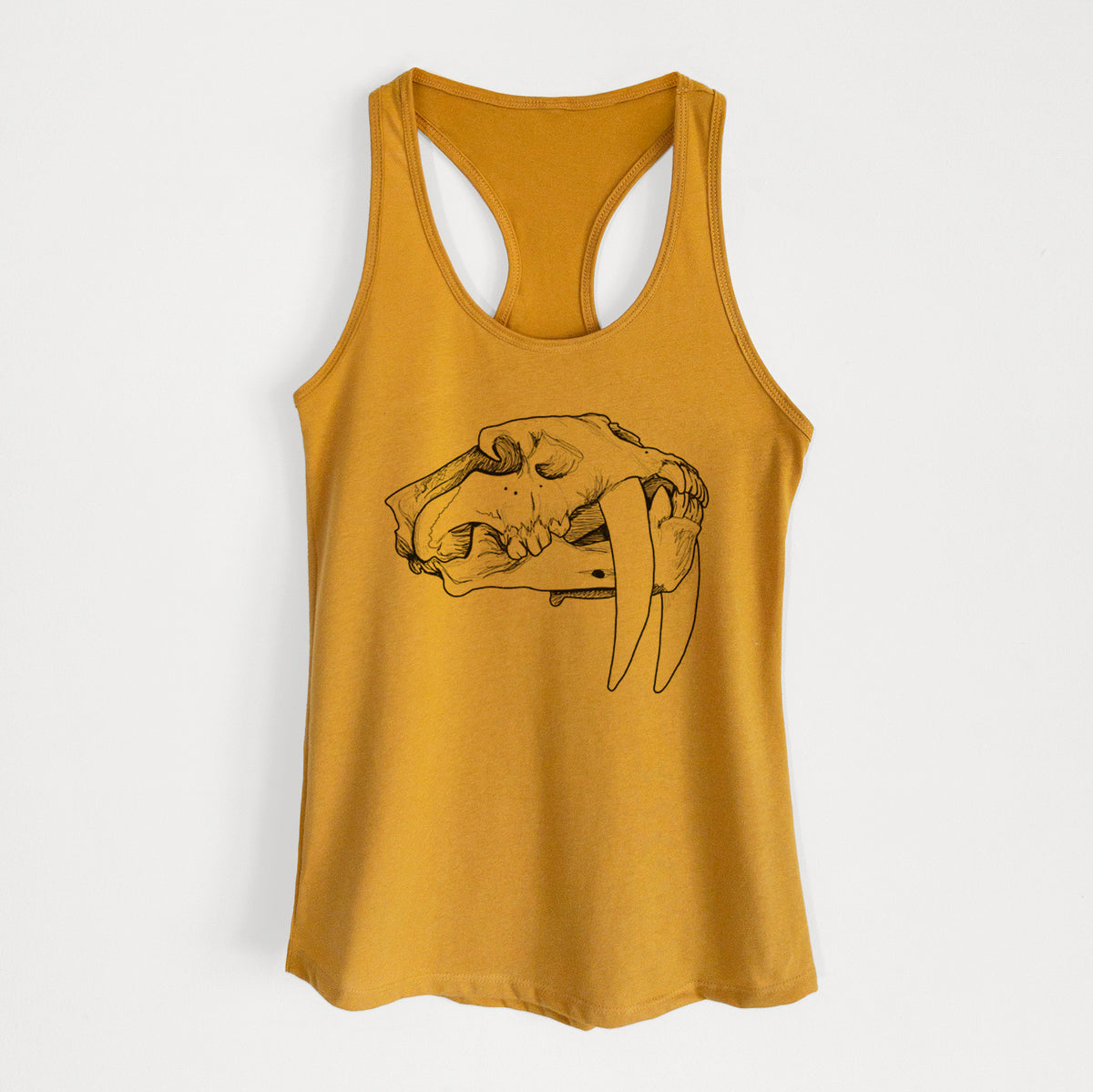 Gold women's racerback tank top laid flat, printed with a detailed black ink illustration of a saber-toothed tiger skull.