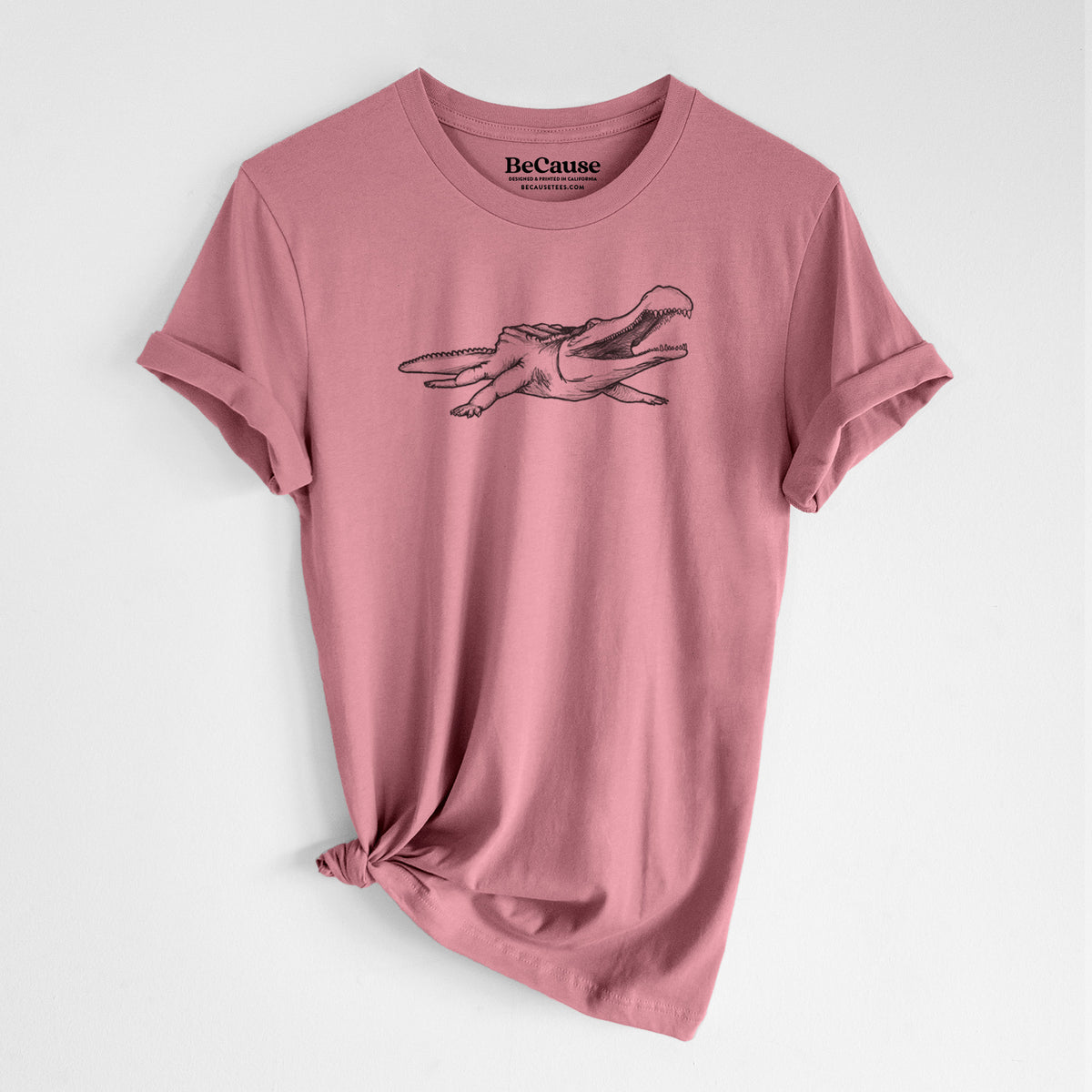 Mauve pink lightweight cotton t-shirt laid flat with the sleeves rolled, printed with a black ink illustration of a Sarcosuchus, a giant prehistoric crocodile.
