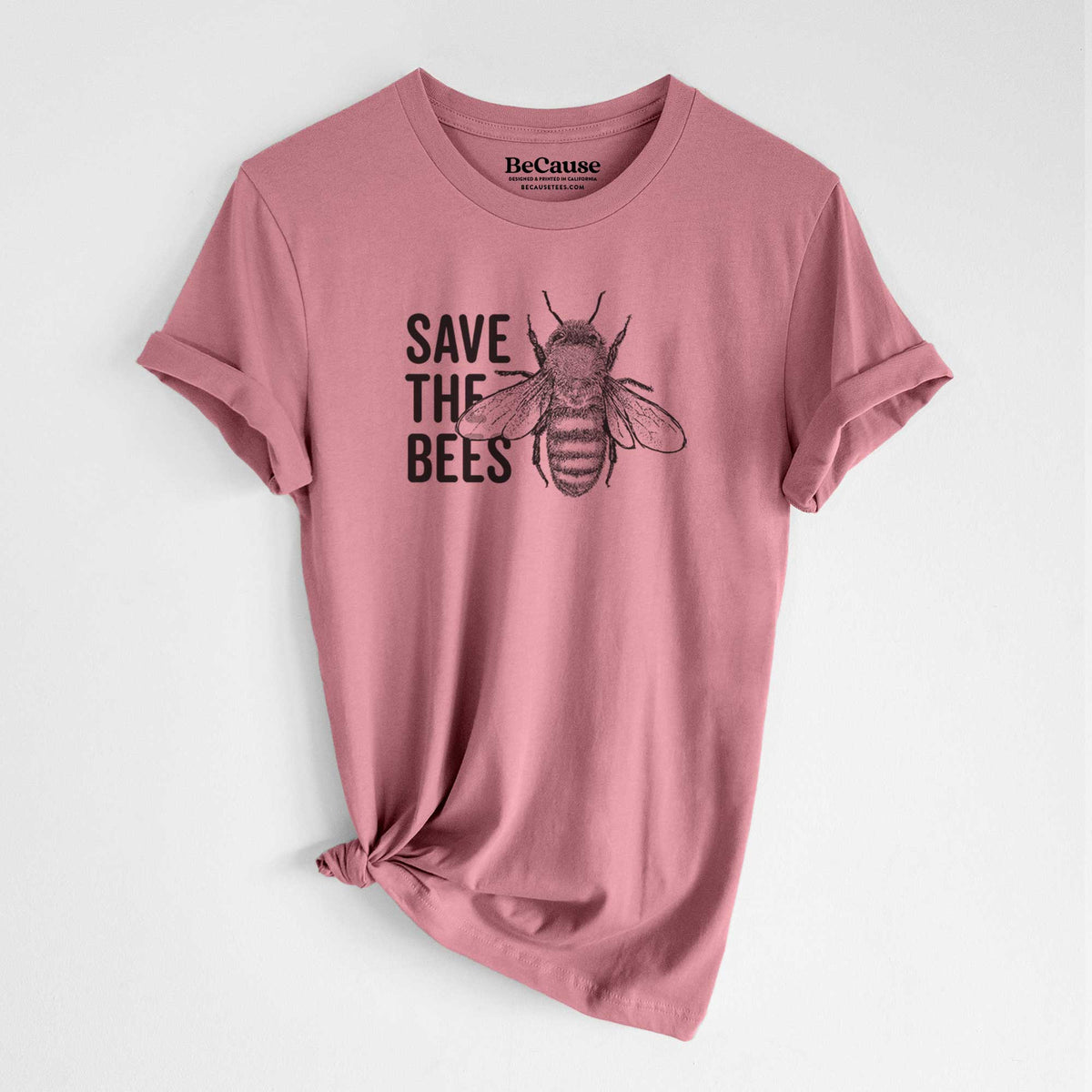 Mauve pink lightweight cotton t-shirt laid flat with the sleeves rolled, printed with bold black words reading Save the Bees beside a detailed honey bee illustration.