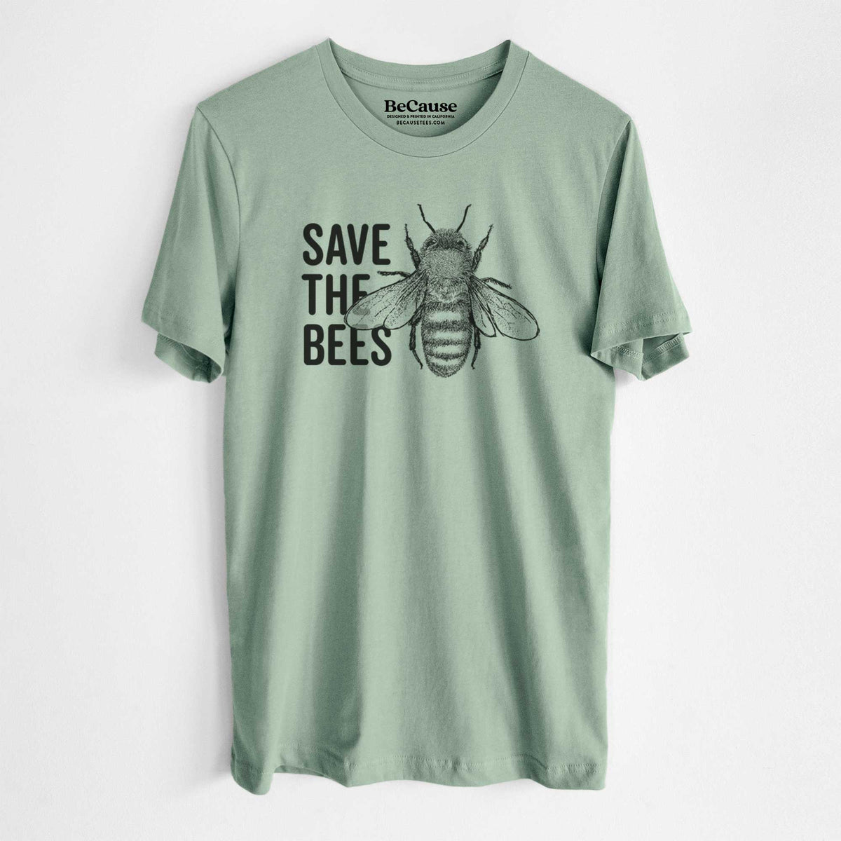 Sage green lightweight cotton t-shirt laid flat, printed with bold black words reading Save the Bees beside a detailed honey bee illustration.
