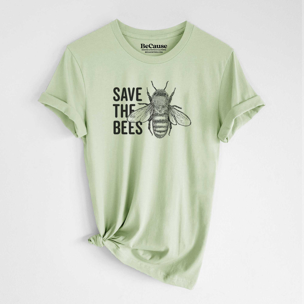 Spring green lightweight cotton t-shirt laid flat with the sleeves rolled, printed with bold black words reading Save the Bees beside a detailed honey bee illustration.