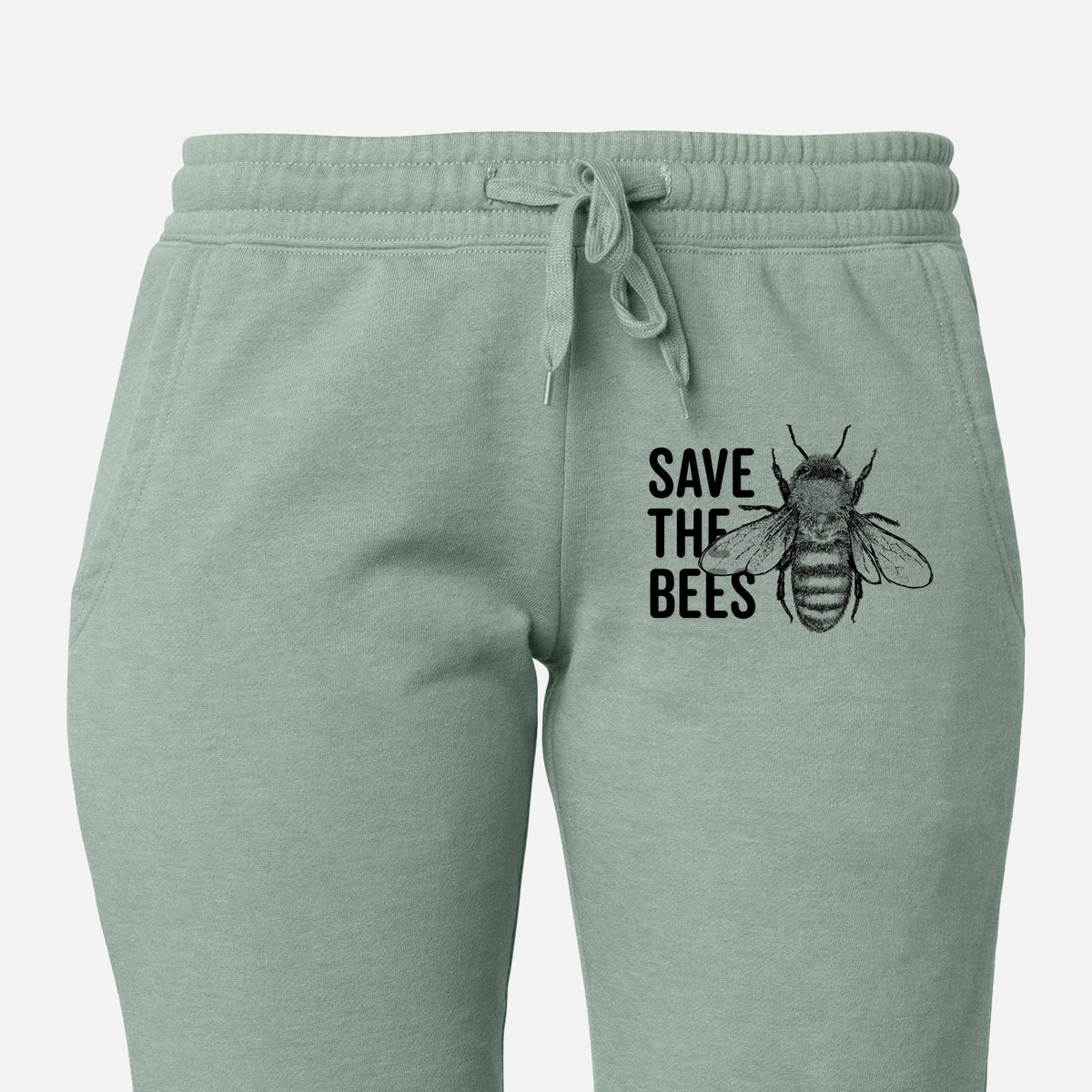 Front of sage green Cali Wave sweatpants, printed with bold black words reading Save the Bees beside a detailed honey bee illustration on the leg.