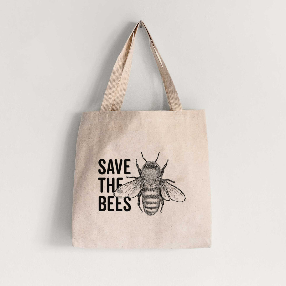 Natural canvas tote bag printed with bold black words reading Save the Bees beside a detailed honey bee illustration.
