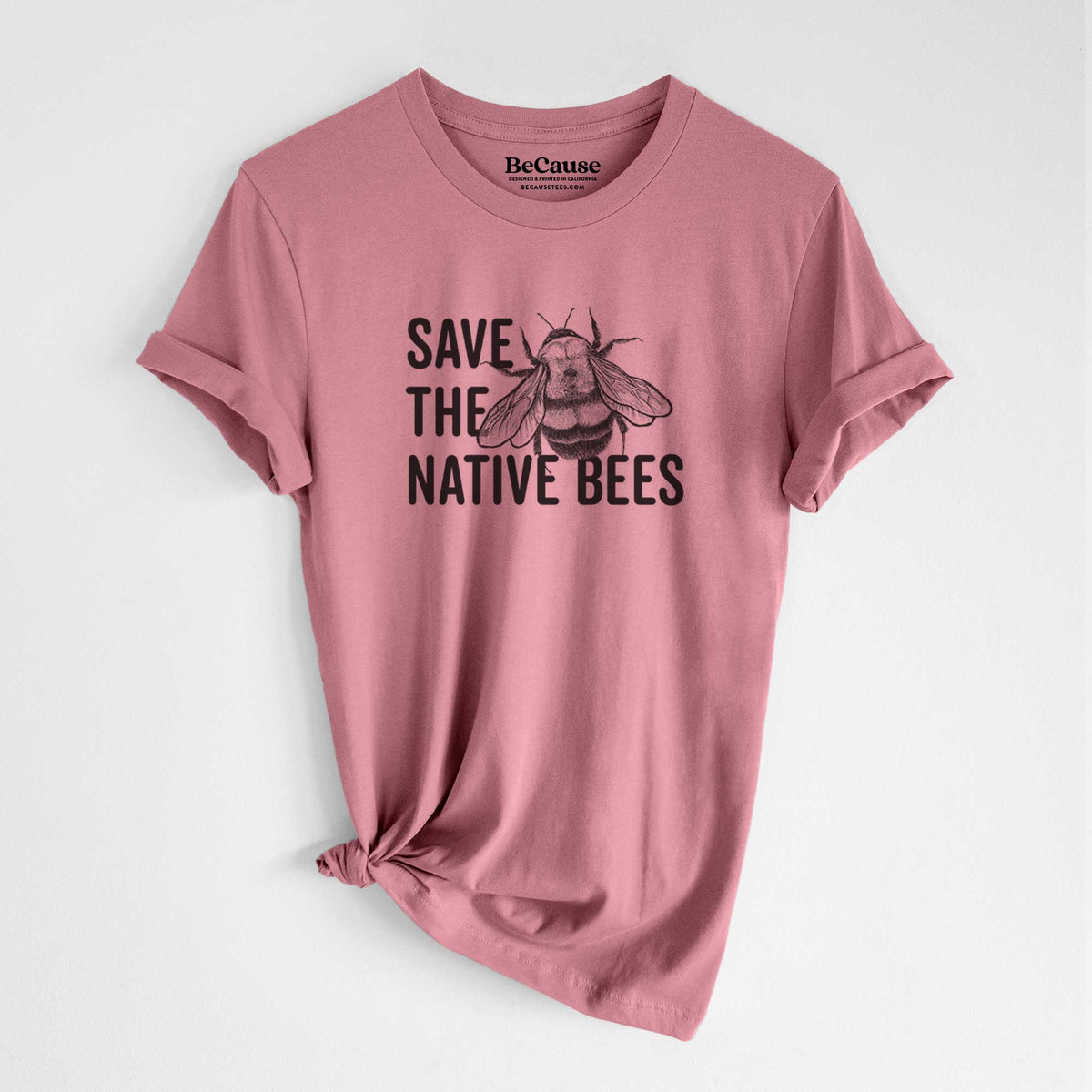 Mauve pink lightweight cotton t-shirt laid flat with the sleeves rolled, printed with bold black words reading Save the Native Bees beside a detailed bee illustration.