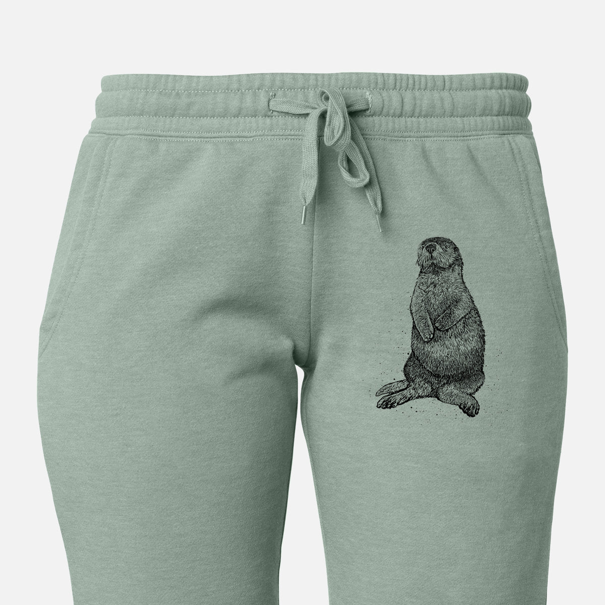 Front of sage green Cali Wave sweatpants, printed with a detailed black ink illustration of a sea otter sitting upright on the leg.