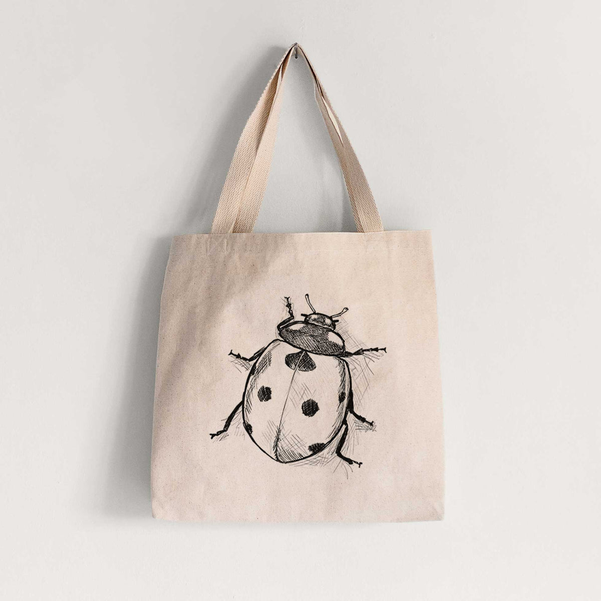 Natural canvas tote bag printed with a detailed black ink illustration of a seven-spot ladybird beetle.