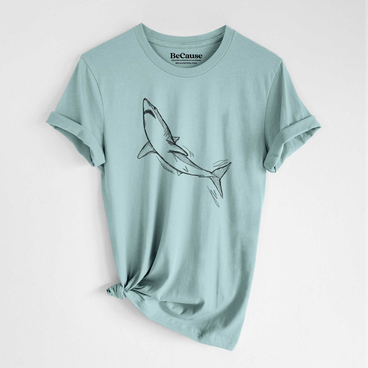 Dusty blue lightweight cotton t-shirt laid flat with the sleeves rolled, printed with a black ink illustration of a shortfin mako shark diving.