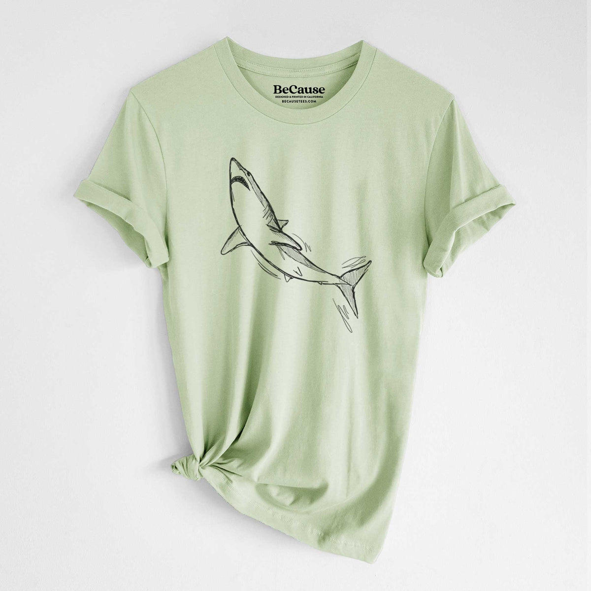 Spring green lightweight cotton t-shirt laid flat with the sleeves rolled, printed with a black ink illustration of a shortfin mako shark diving.