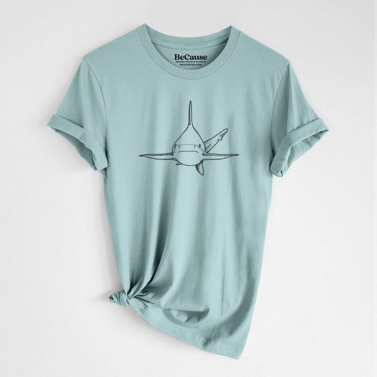 Dusty blue lightweight cotton t-shirt laid flat with the sleeves rolled, printed with a black ink illustration of a silvertip shark swimming head-on.