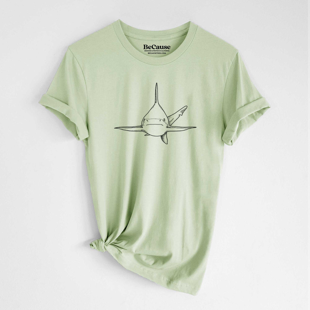Spring green lightweight cotton t-shirt laid flat with the sleeves rolled, printed with a black ink illustration of a silvertip shark swimming head-on.