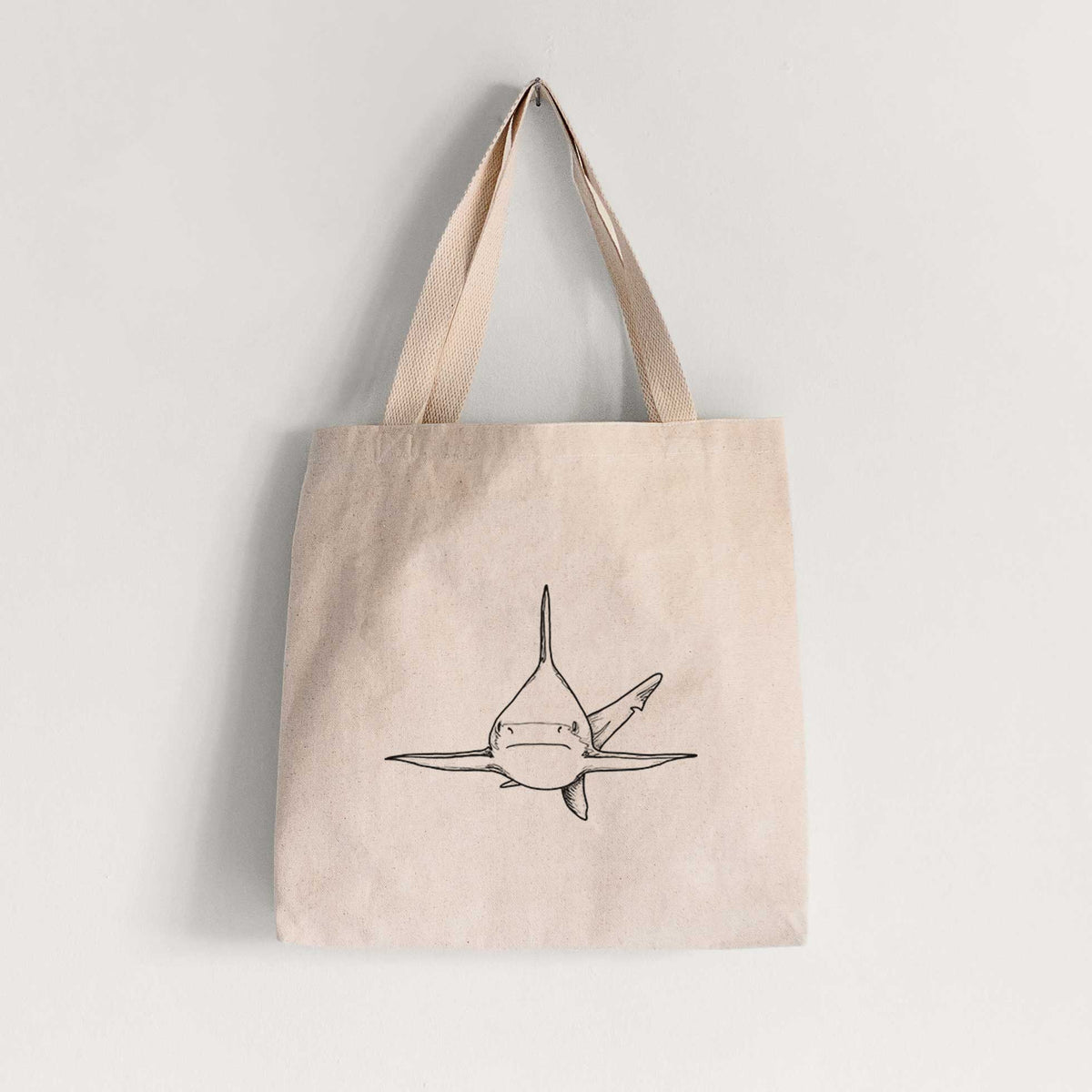 Natural canvas tote bag printed with a black ink illustration of a silvertip shark swimming head-on.