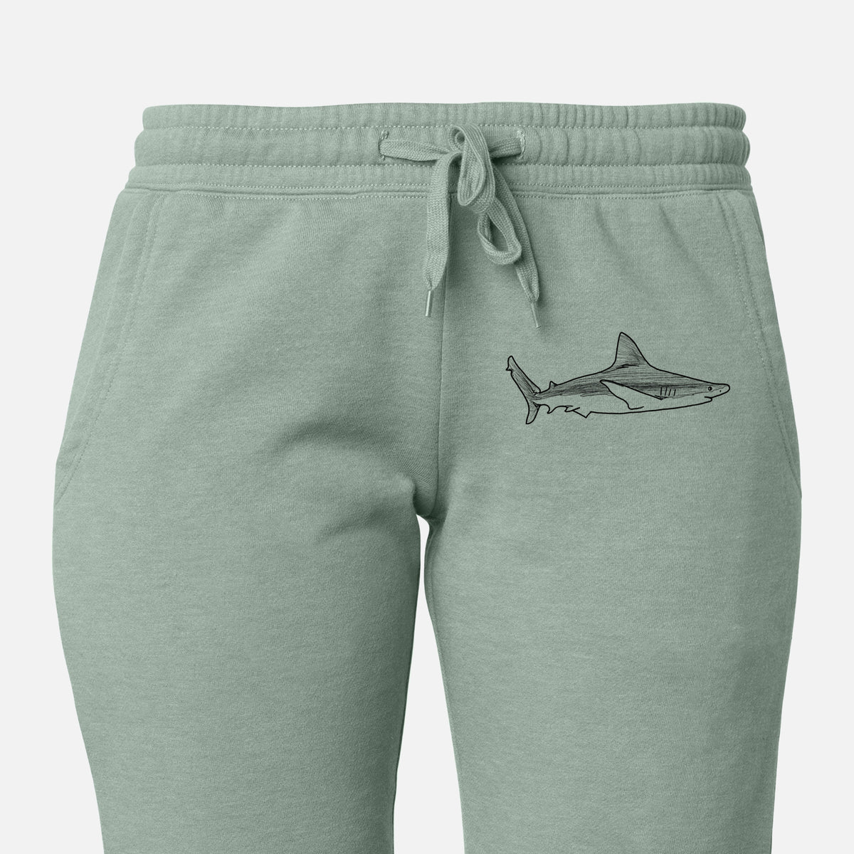 Front of sage green Cali Wave sweatpants, printed with a black ink illustration of a silvertip shark swimming in profile on the leg.