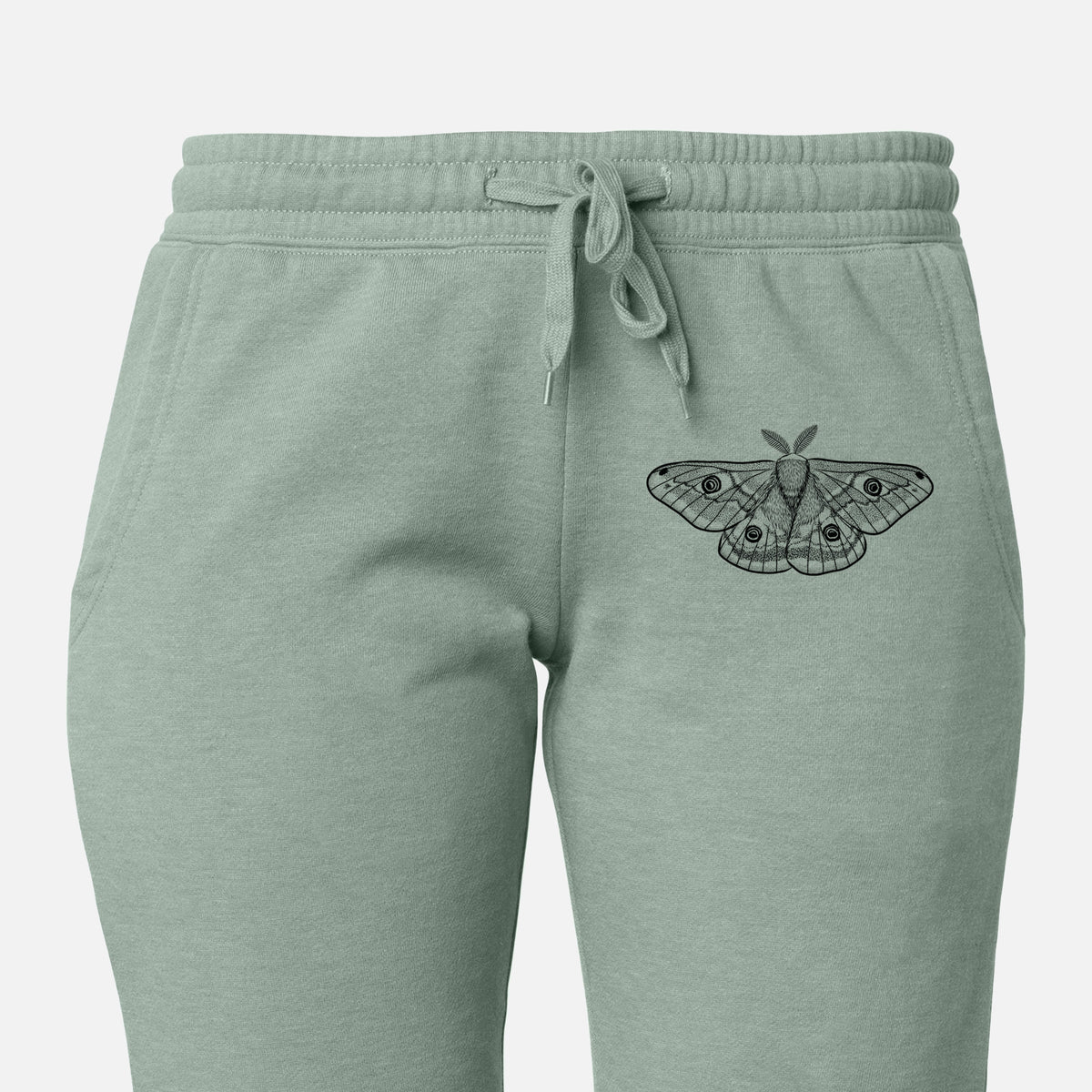 Front of sage green Cali Wave sweatpants, printed with a detailed black ink illustration of a small emperor moth with eyespots on its wings on the leg.