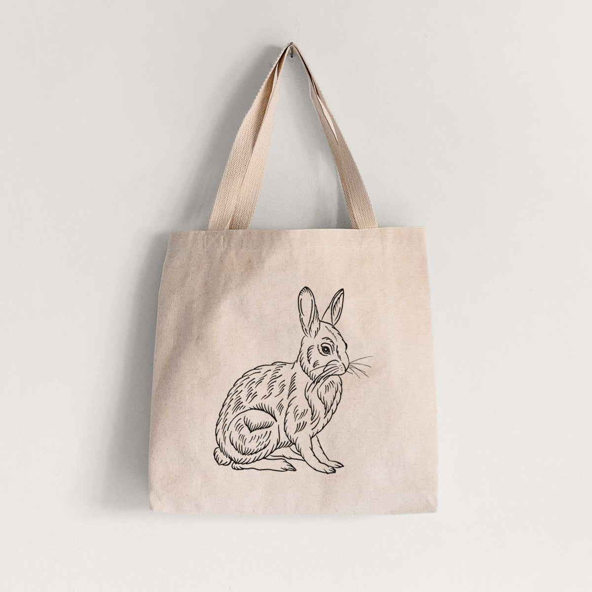 Natural canvas tote bag printed with a detailed black ink illustration of a snowshoe hare sitting upright.