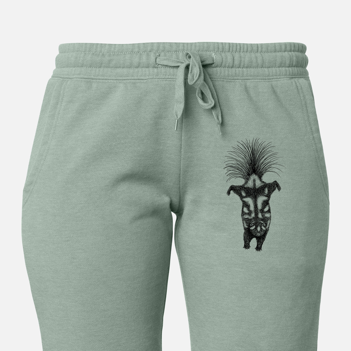 Front of sage green Cali Wave sweatpants, printed with a black ink illustration of a spotted skunk doing a handstand with its tail fanned on the leg.