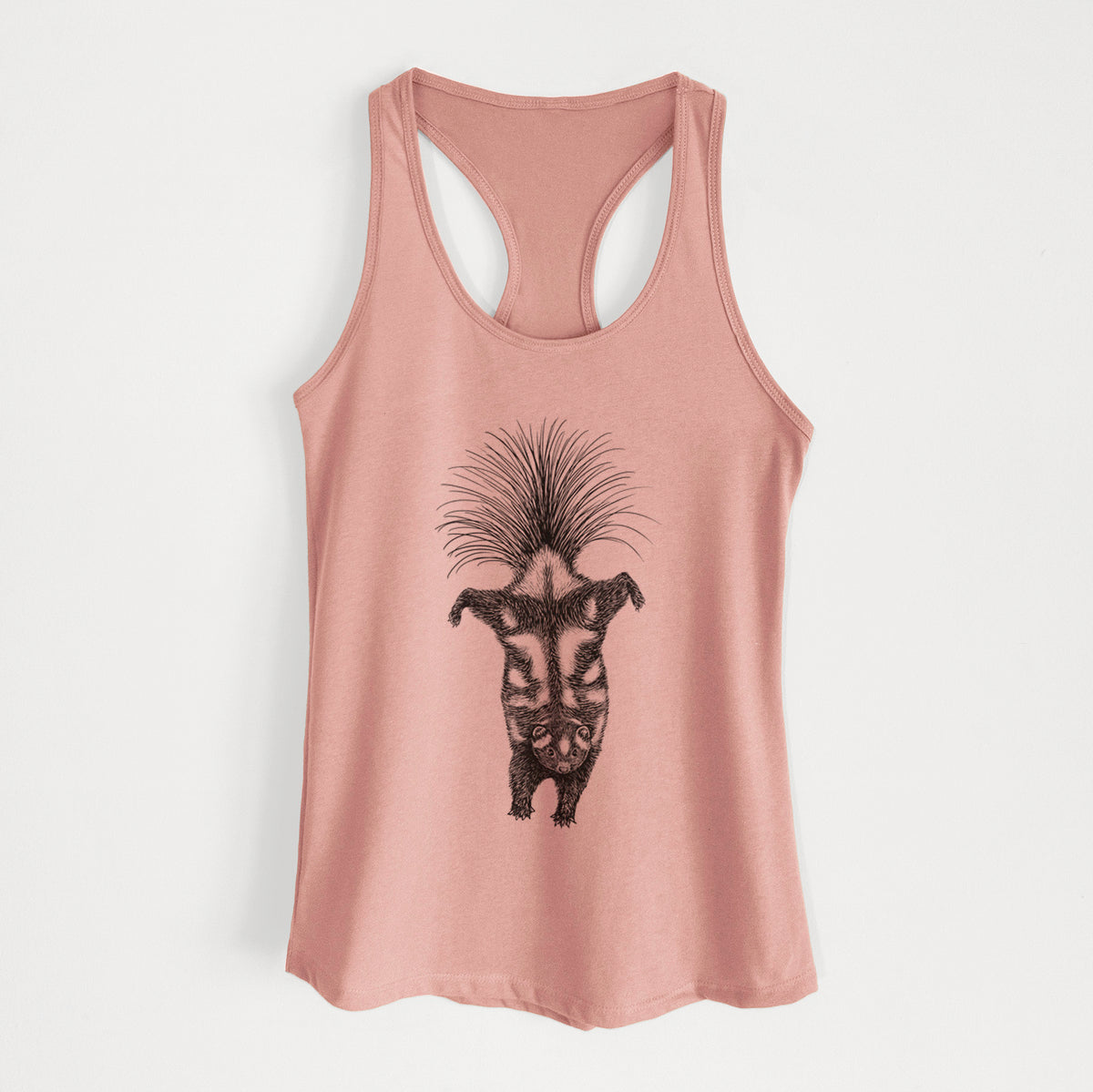 Desert pink women's racerback tank top laid flat, printed with a black ink illustration of a spotted skunk doing a handstand with its tail fanned.