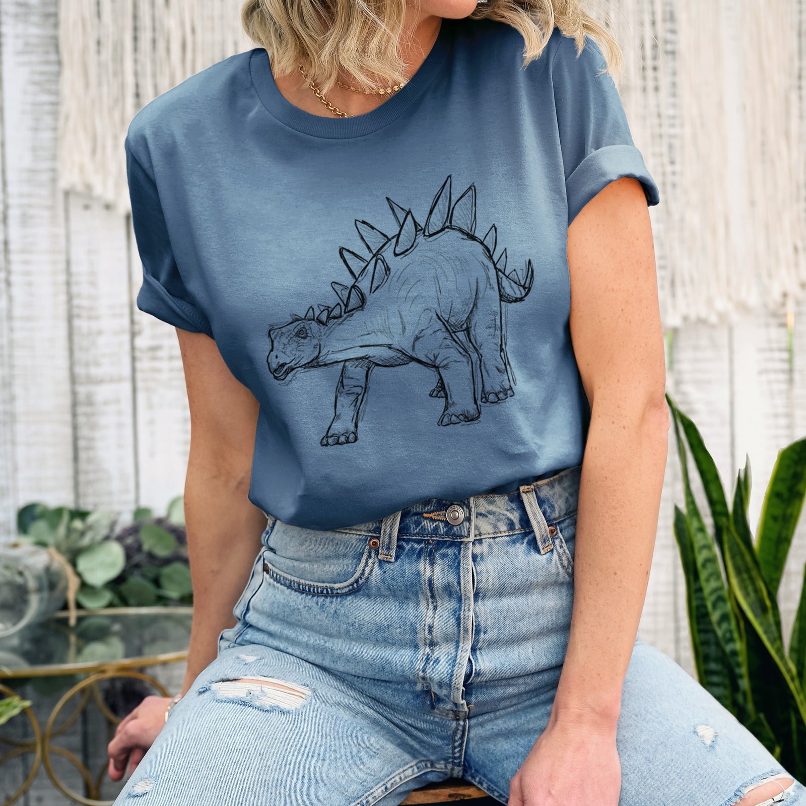 Autumn lightweight cotton t-shirt laid flat, printed with a black ink illustration of a Stegosaurus with plates along its back.