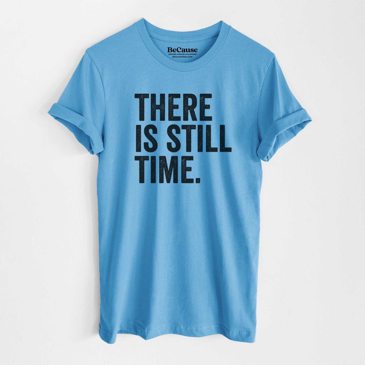 Ocean blue lightweight cotton t-shirt laid flat, printed with bold black words reading There Is Still Time.