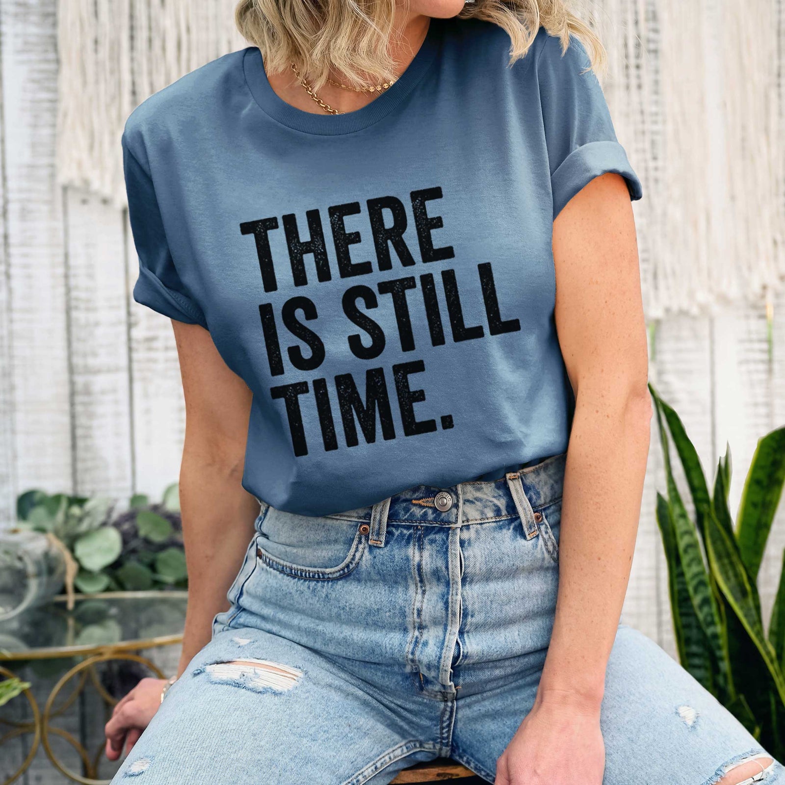Leaf green lightweight cotton t-shirt laid flat, printed with bold black words reading There Is Still Time.