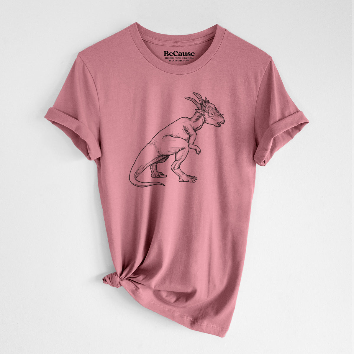 Mauve pink lightweight cotton t-shirt laid flat with the sleeves rolled, printed with a black ink illustration of a Stygimoloch dinosaur with a spiky domed head.