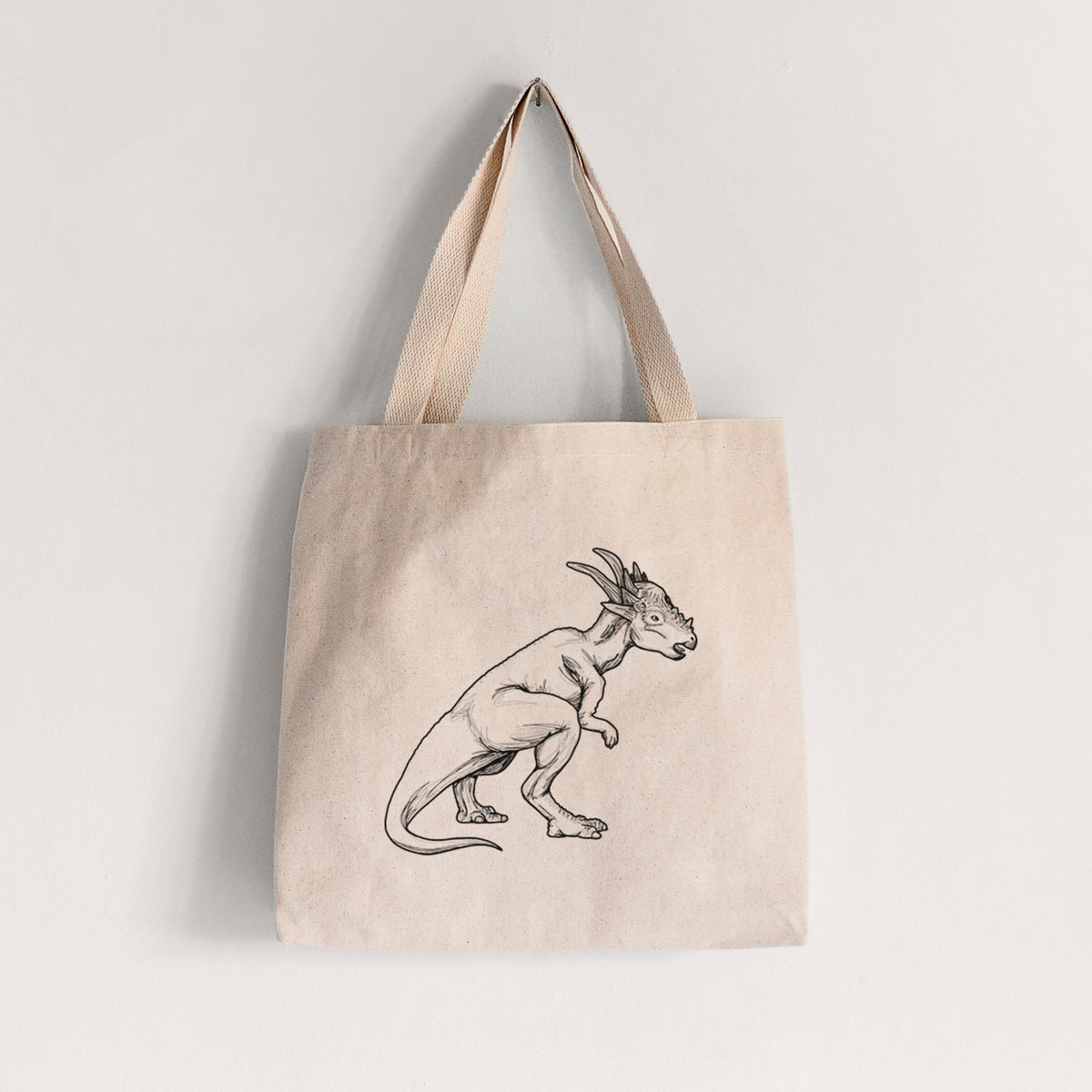 Natural canvas tote bag printed with a black ink illustration of a Stygimoloch dinosaur with a spiky domed head.
