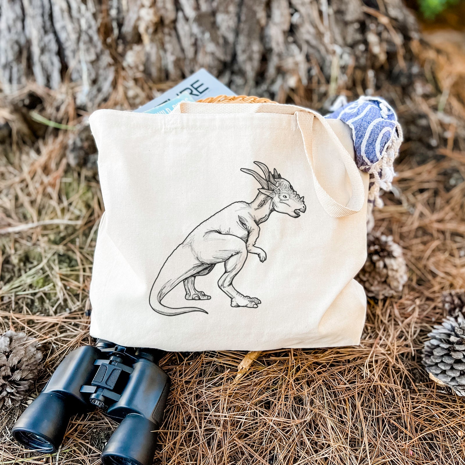 Natural canvas tote bag printed with a black ink illustration of a Stygimoloch dinosaur with a spiky domed head.