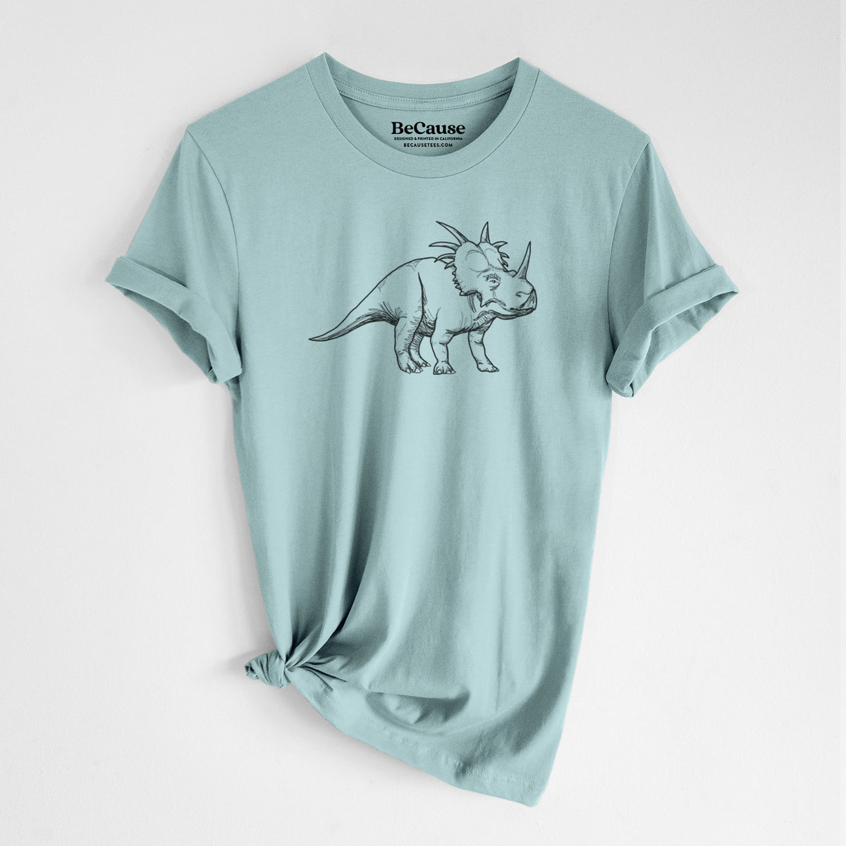 Dusty blue lightweight cotton t-shirt laid flat with the sleeves rolled, printed with a black ink illustration of a Styracosaurus with its spiked frill.