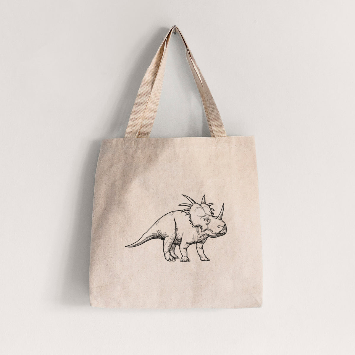 Natural canvas tote bag printed with a black ink illustration of a Styracosaurus with its spiked frill.