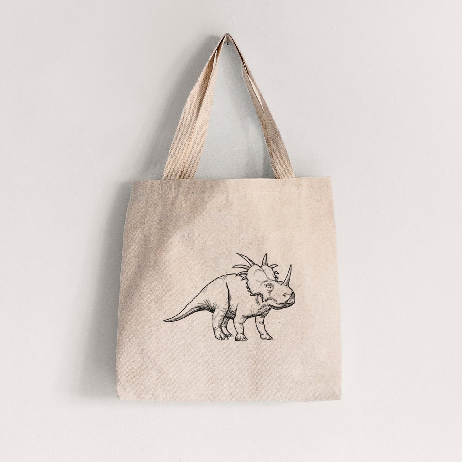 Natural canvas tote bag printed with a black ink illustration of a Styracosaurus with its spiked frill.