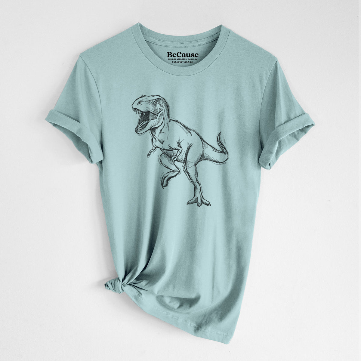 Dusty blue lightweight cotton t-shirt laid flat with the sleeves rolled, printed with a black ink illustration of a Tyrannosaurus rex roaring.