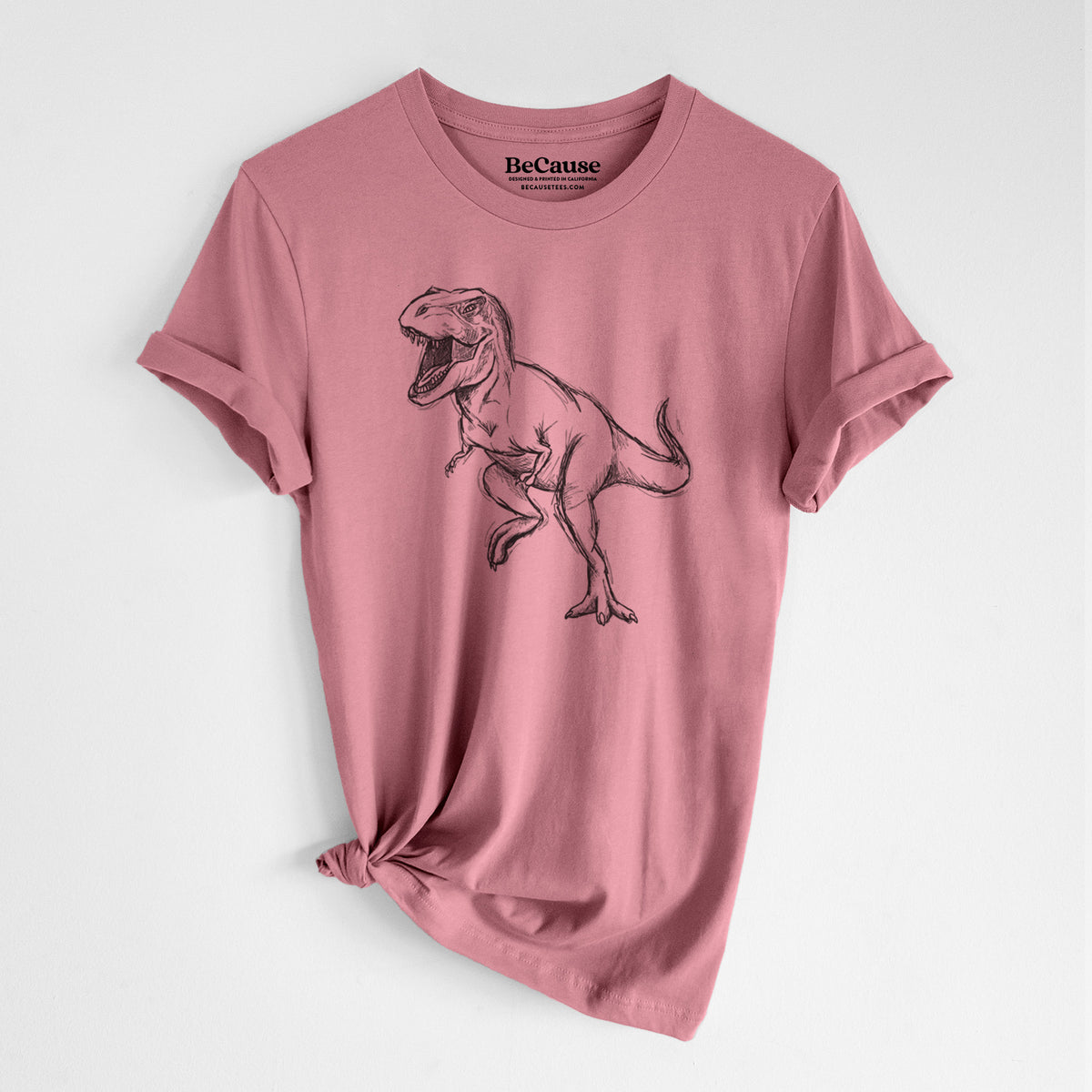 Mauve pink lightweight cotton t-shirt laid flat with the sleeves rolled, printed with a black ink illustration of a Tyrannosaurus rex roaring.