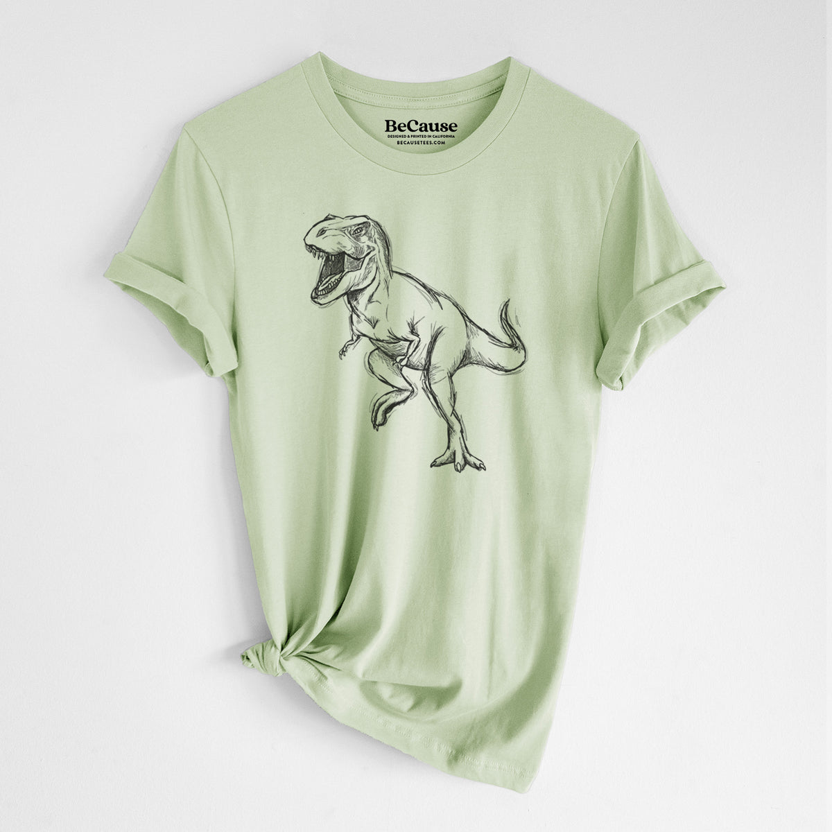 Spring green lightweight cotton t-shirt laid flat with the sleeves rolled, printed with a black ink illustration of a Tyrannosaurus rex roaring.