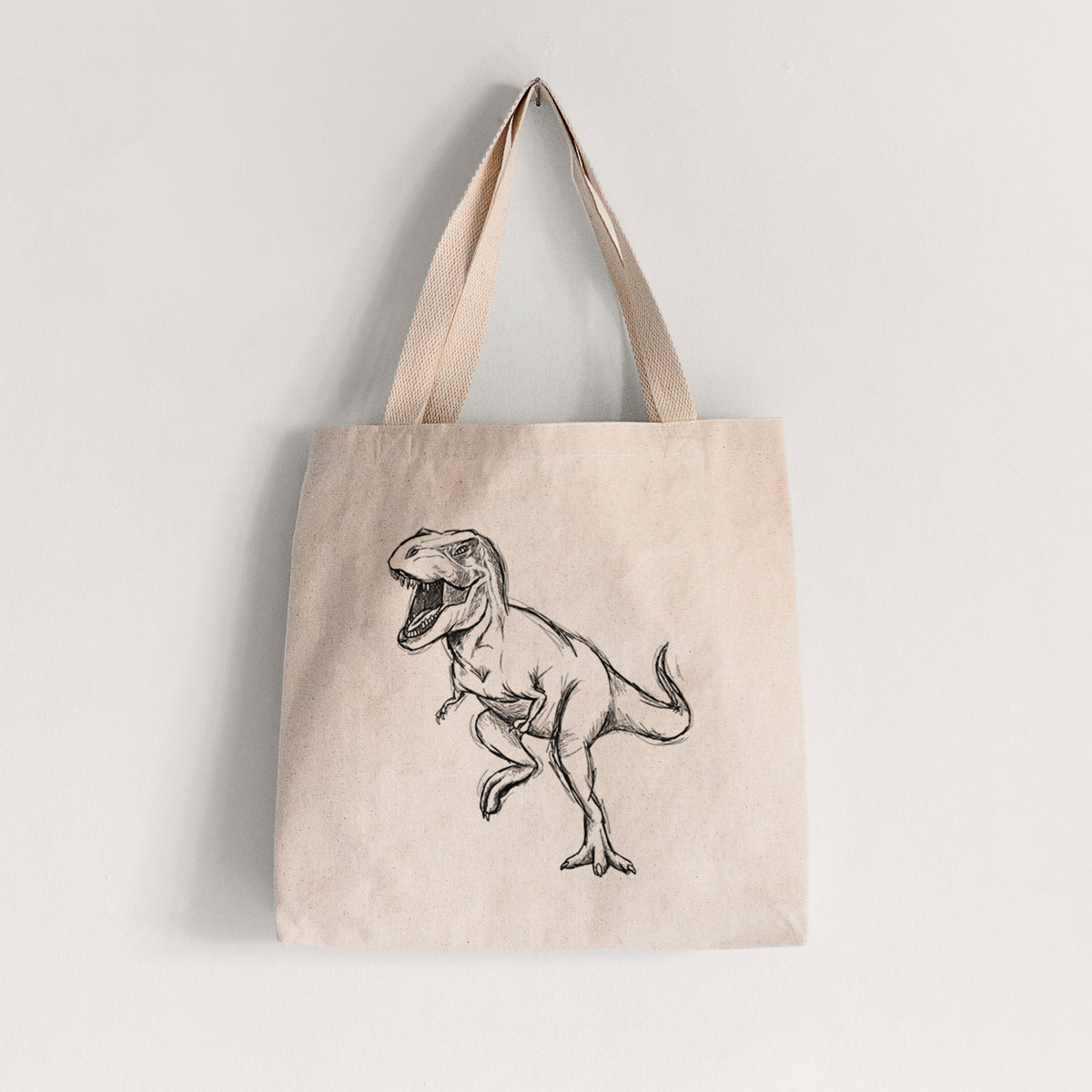 Natural canvas tote bag printed with a black ink illustration of a Tyrannosaurus rex roaring.