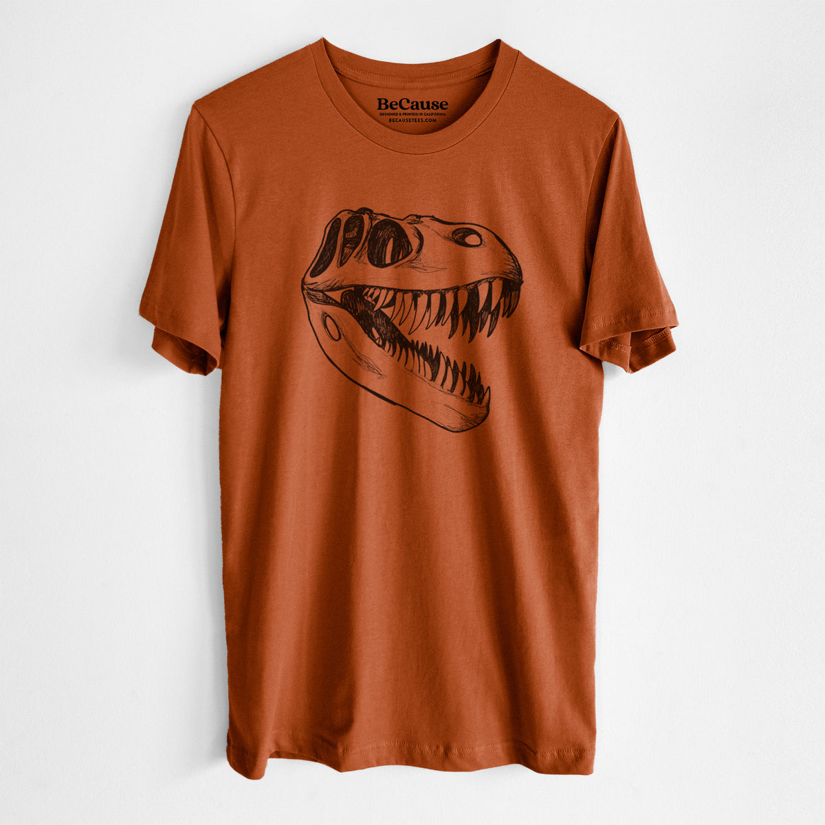 Autumn lightweight cotton t-shirt laid flat, printed with a black ink illustration of a Tyrannosaurus rex skull with sharp teeth.