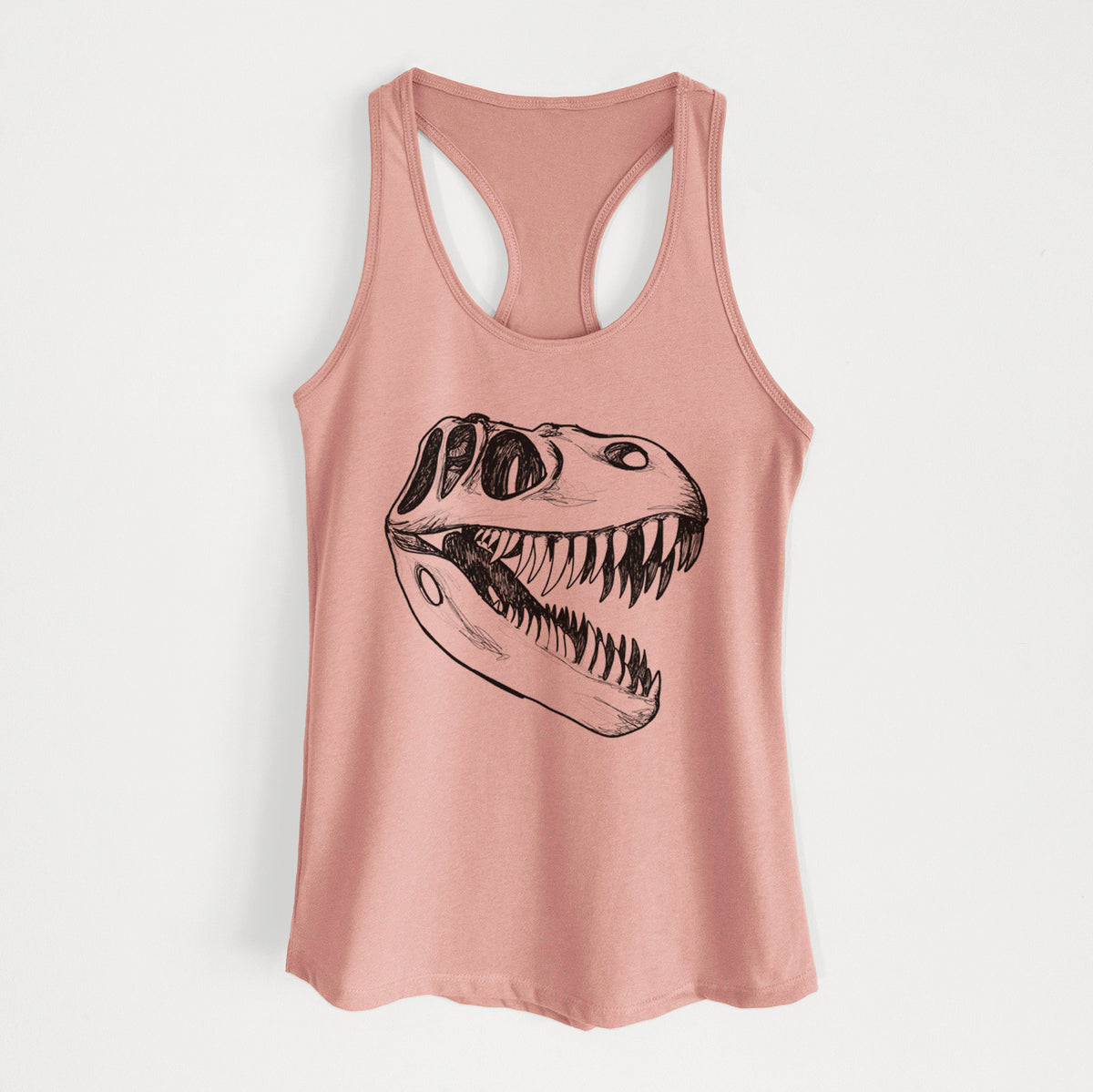 Desert pink women's racerback tank top laid flat, printed with a black ink illustration of a Tyrannosaurus rex skull with sharp teeth.