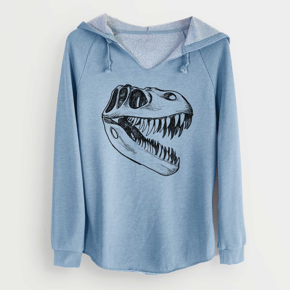 Misty blue women's Cali Wave hooded sweatshirt laid flat, printed with a black ink illustration of a Tyrannosaurus rex skull with sharp teeth.